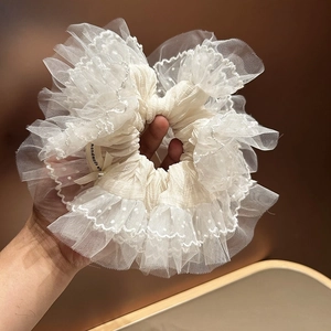 Gros plan d'un grand chouchou en dentelle blanche avec tulle à pois et étiquette fait main