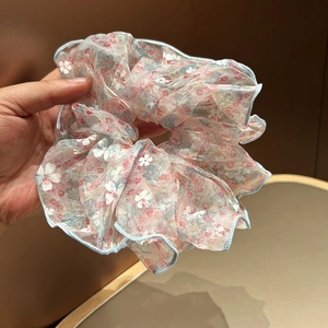 Détail d'un chouchou en organza à fleurs roses avec des bords bleu clair soyeux