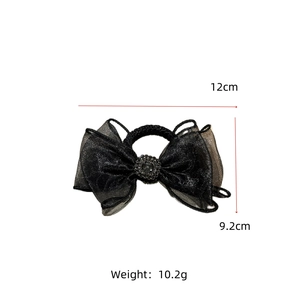 Detail view of black mesh bow hair tie with rhinestone center showing 12cm dimensions