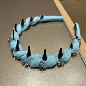 Detail view of light blue twisted headband with black crystal spikes and anti-slip comb teeth