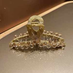 Gros plan sur une pince à cheveux en cristal ambre avec tissu doré et ressort métal