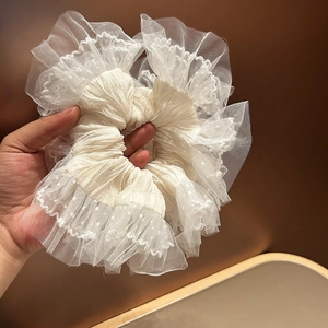 Détail du chouchou géant en dentelle blanc cassé avec tulle à pois et couches volantées