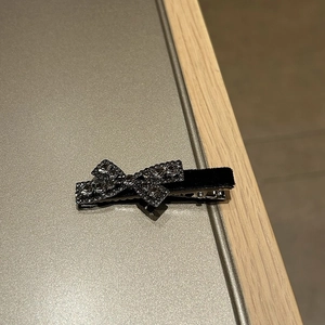 Close-up of black velvet bow hair clip with sparkling rhinestones and metal alligator grip