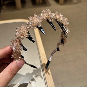 Detail of crystal flower headband featuring five champagne stones and black non-slip teeth