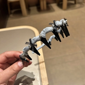 Detail of grey fabric hairband featuring multiple black clips with rhinestone bows