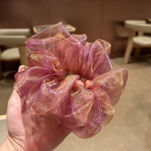 Gros plan d'un chouchou en organza lavande avec des reflets dorés et des plis élégants