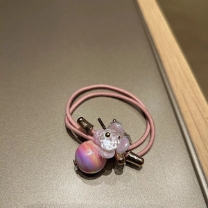 Detail of pink elastic hair tie with translucent purple flower and iridescent round bead