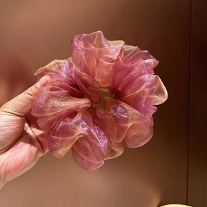 Détail d'un chouchou élégant en tulle avec motif floral rose et paillettes dorées fines