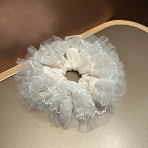 Détail macro du chouchou en dentelle blanche avec mesh multicouche et pois brodés