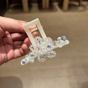Close-up of cream crystal hair claw clip with iridescent beads for elegant hair styling