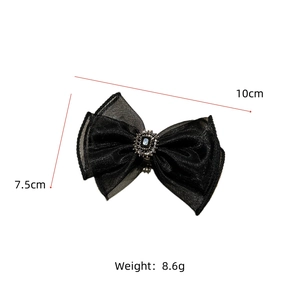 Detail of a black organza bow hair clip with vintage rhinestone center, 10cm x 7.5cm