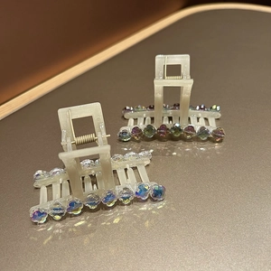 Détail de pinces à cheveux crème avec perles de cristal arc-en-ciel et ressort métal