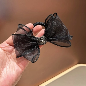 Close-up of black mesh bow hair tie with sparkling rhinestone centerpiece and elastic band