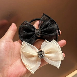 Detailed view of organza bow hair clips with crystal centerpieces in black and beige