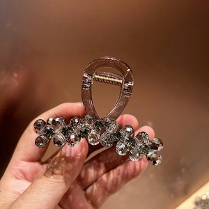 Detail of a brown rhinestone claw clip held in hand showing sparkling grey crystal beads