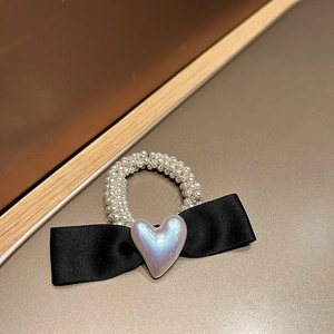 Détail d'un chouchou en satin noir avec un accent de perle en forme de cœur irisé