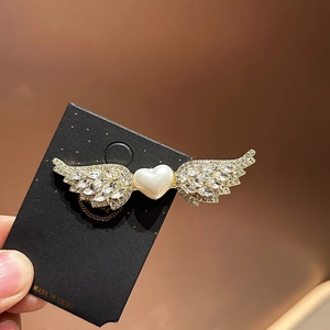 Primer plano del pasador de alas de ángel con forma de corazón y diamantes
