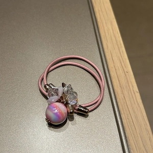 Detail of pink elastic hair tie with gradient faceted crystal beads and gold metal accents