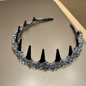 Dettaglio di cerchietto punk gothic con punte nere coniche e decorazioni in cristallo
