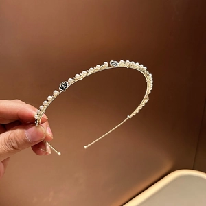 Dettaglio del cerchietto dorato fatto a mano con perle bianche e piccoli fiori neri