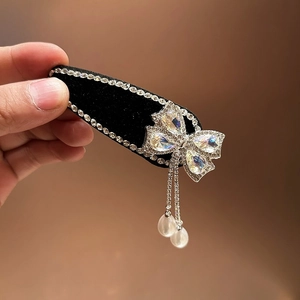 Detail van fluwelen haarklem met strass vlinder en hanger van parel kwastjes