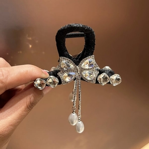 Detail van de zwarte haarklem met een strass-strikje en elegante parelkwastjes