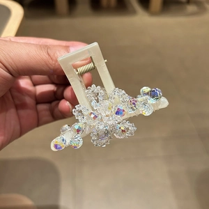 Detail of a beige hair claw clip with shimmering multifaceted crystals and metal spring