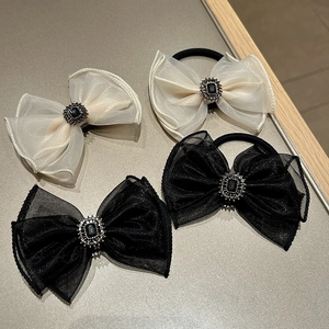 Detail of organza bow hair clips with central black gemstones and rhinestone borders