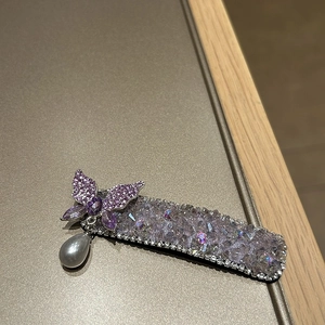 Detail einer luxuriösen lila Kristall-Schmetterlings-Haarklammer mit einer grauen Perle
