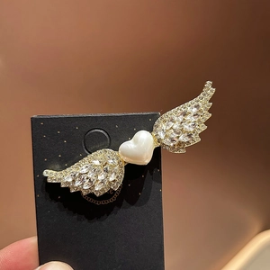 Pinza para el pelo dorada con alas de cristales y perla en forma de corazón