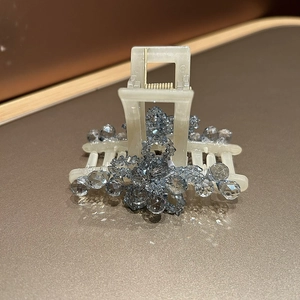 Detail of crystal flower hair claw clip with blue gems on creamy white plastic