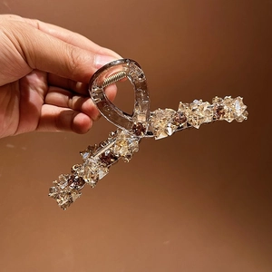 Gros plan détaillé des cristaux champagne et café sur une pince à cheveux en acrylique