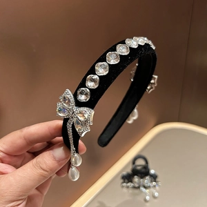 Detailopname van zwarte fluwelen haarband met kristallen strik en parelhanger