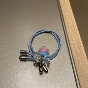 Detailed macro view of sky blue elastic hair tie with crystal flower and iridescent bead