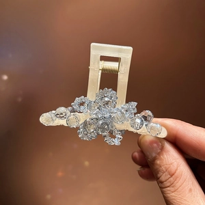 Macro detail of medium crystal hair claw with handwoven resin beads and floral design