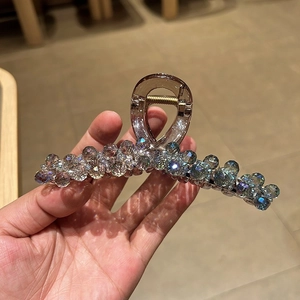 Détail d'une pince à cheveux en perles de cristal avec ressort doré et perles brunes