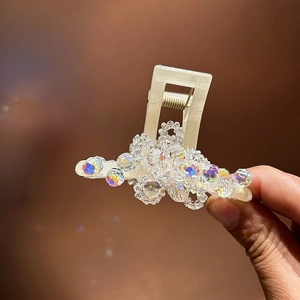 Detailed macro view of an elegant cream hair claw clip with colorful shimmering crystal beads