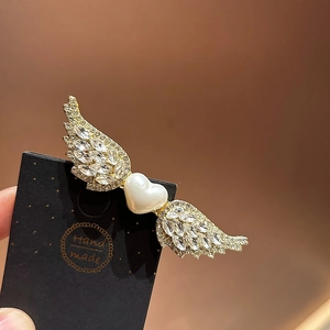 Elegante pinza de alas de ángel con perla de corazón y cristales en base dorada