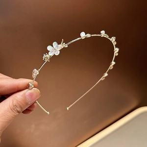 Détail du serre-tête en alliage doré avec fleurs nacrées et strass brillants décoratifs