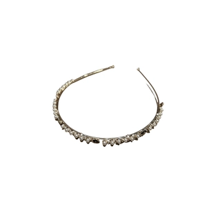 Elegante cerchietto in metallo dorato con perle bianche e strass scintillanti su sfondo bianco