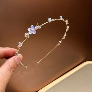 Détail d'un serre-tête en alliage doré avec fleurs en cristal violet et perles bleues