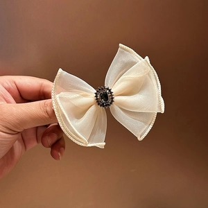 Detailed view of cream organza bow hair clip with vintage dark gemstone and crystals