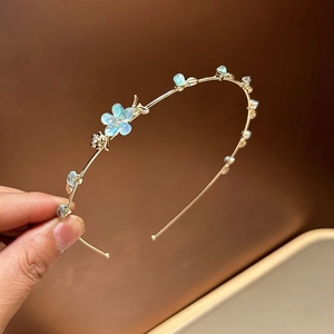 Détail du serre-tête doré avec fleurs bleu clair et perles en forme de goutte d'eau