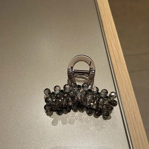 Macro shot of dark grey multifaceted rhinestones on a luxury hair claw clip with metal spring