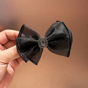 Close-up of black organza bow hair clip featuring a grey rhinestone and crystal detail