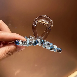 Gros plan d'une pince à cheveux perlée avec cristaux bleus et monture en plastique ambre