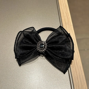 Detail of black organza bow hair tie with dark gemstone and shimmering rhinestones