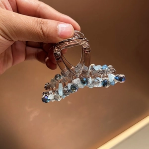 Détail d'une pince à cheveux marron translucide ornée de perles de cristal bleues