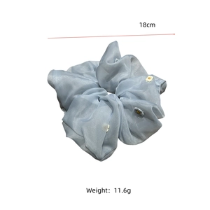 Detail of a 18cm light blue organza scrunchie with tiny embroidered daisy patterns