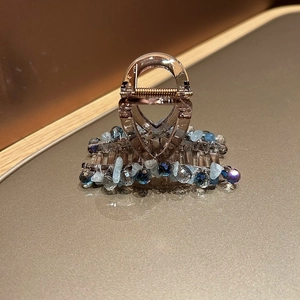Détail macro de la pince à cheveux en résine ambre avec perles de cristal bleu et ressort
